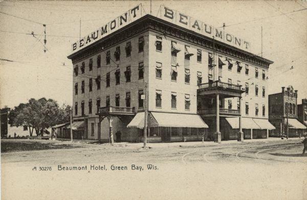 Illustrated postcard of the Beaumont Hotel. Balconies are over the entrance and awnings are over the windows. Caption reads: "Beaumont Hotel, Green Bay, Wis."