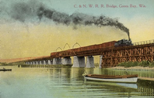 View of a train crossing a railroad bridge over the Fox River. Rowboats are in the river and docked at a pier in the foreground. Caption reads: "C. & N. W. R. R. Bridge, Green Bay, Wis."