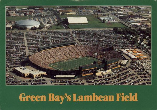 Aerial view of Lambeau Field on game day. Veterans Coliseum in the background.

Text on reverse reads: "The home stadium of the Green Bay Packers, built in 1957, has a present seating capacity of 56,926 with the completion of private boxes in August, 1985. Home games are consistently sold out on a season-ticket basis."