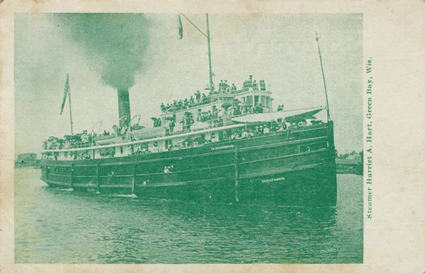 View across water towards the Steamer "Harriet A. Hart," with many passengers on board, and smoke coming out of the smokestack. Caption reads: "Steamer Harriet A. Hart, Green Bay, Wis."