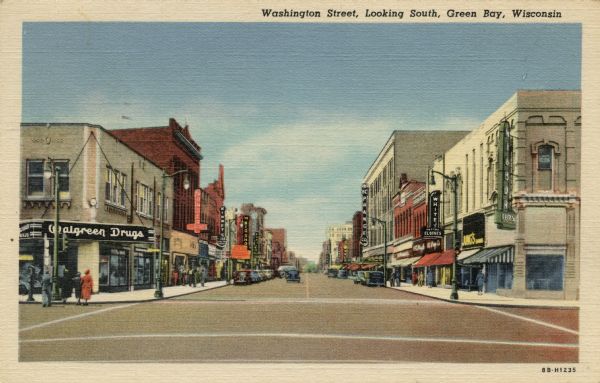 Colorized postcard view down street towards a shopping district, which is lined with shops: Walgreen's, Prange's, and Kinney Shoes. Automobiles are parked along the curbs. Caption reads: "Washington Street, Looking South, Green Bay, Wis."