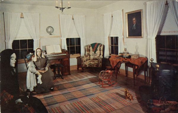 Ektachrome postcard of the front parlor, with mannequins of women dressed in period clothing sitting in chairs.

Text on reverse reads: "The Front Parlor or sitting room was used mostly by women and children travelers. They could rest here during the interval needed to feed or change horses, or they could wile away the early evening hours visiting with other women and children until each guest was issued a candle or lamp and sent to bed."
