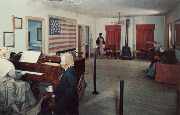 Ektachrome postcard of the Wade House ballroom.

Text on reverse reads: "The Ballroom was the scene of dances, concerts, shows and lectures, a social center for the Greenbush community as well as a place of entertainment for Wade House guests. The American Flag on the wall has 30 stars. Wisconsin became the 30th state in 1848. The costumes worn by the mannequins are authentic, not reproductions. Many of them were found in the Wade House."
