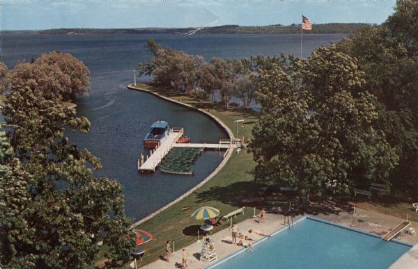 Color elevated view of Inspiration Point on Green Lake. The swimming pool is in the foreground. At a dock are several moored rowboats and an excursion boat.

Text on reverse reads: "One of the Assembly's loveliest spots is Inspiration Point, with its view of the yacht harbor, the island and the swimming pool."