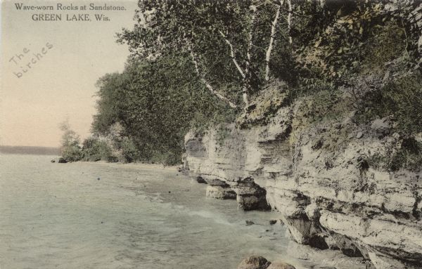 View of sandstone cliffs on the shore of Green Lake. Caption reads: "Wave-worn Rocks at Sandstone, Green Lake, Wis."