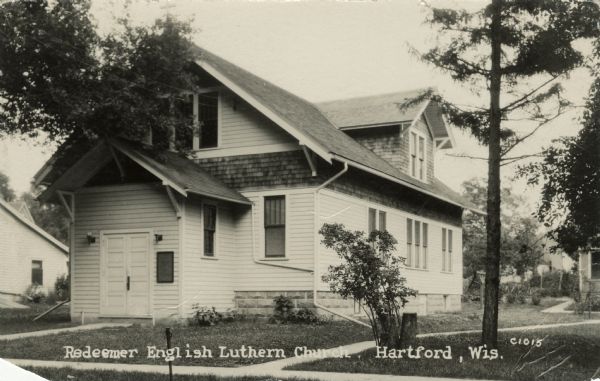 View from street towards the front of a wood-frame church with a second floor. Caption reads: "Redeemer English Lutheran Church, Hartford, Wis."