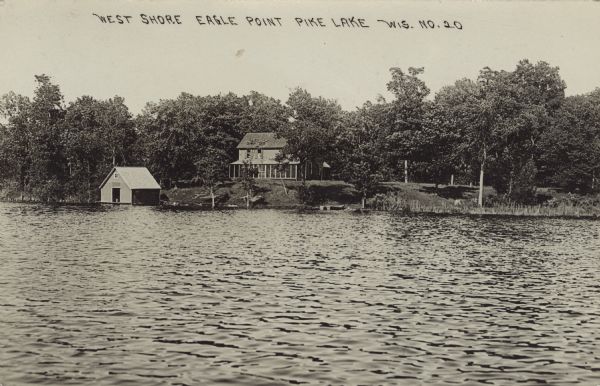 View across water towards a lake house with a screened-in porch, and a boathouse at the shoreline. Caption reads: "West Shore, Eagle Point, Pike Lake, Wis."