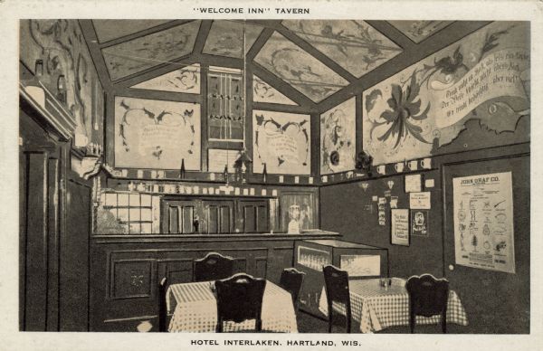 Interior view of the "Welcome Inn" Tavern at the Hotel Interlocken. The painted walls have a German theme. Beer steins are displayed on the shelf above the bar. A rack of postcards and other signs are posted on the wall on the right. Caption at top reads: "'Welcome Inn' Tavern." Caption at bottom reads: "Hotel Interlaken, Hartland, Wis."