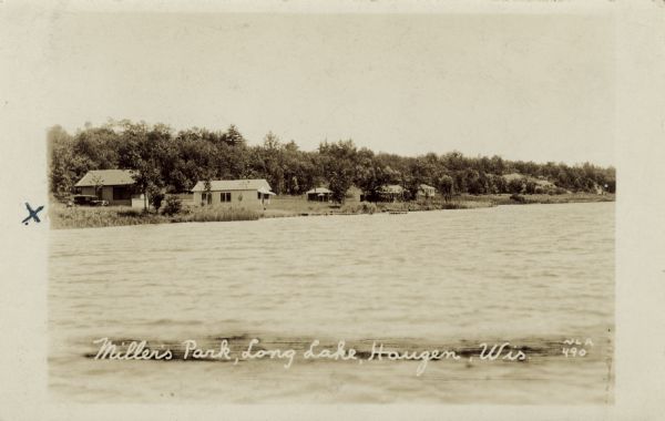 View across water towards the shoreline of Long Lake, with lakeside cottages. Caption reads: "Miller's Park, Long Lake, Haugen, Wis."