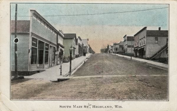 Colorized postcard street view of a central business district in a small town. The post office is on the corner on the left. Caption reads: "South Main St., Highland, Wis."