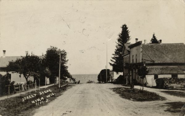 View of a small town street headed toward Lake Michigan. Businesses are on the right, and dwellings are on the left.