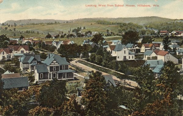 Elevated view of a Hillsboro neighborhood. Rolling hills are in the background. Caption reads: "Looking West from Schoolhouse, Hillsboro, Wis."