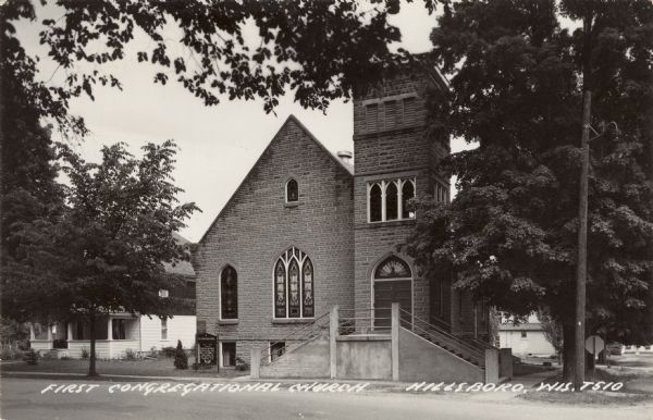 View across street towards the church. The entrance and steeple are on the right. Caption reads: "First Congregational Church, Hillsboro, Wis."