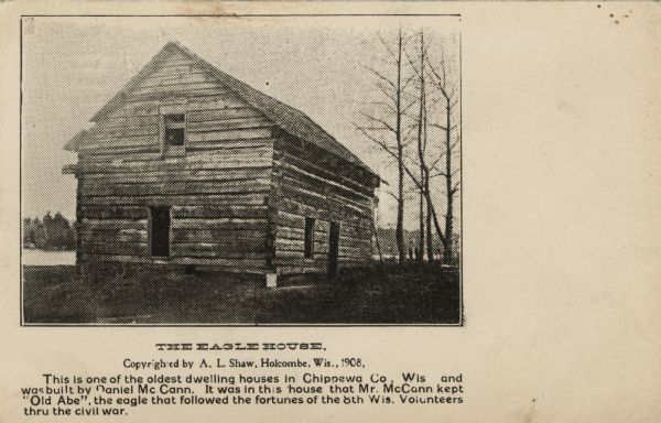 A log cabin next to the Chippewa River.<p>Text reads: "The Eagle House<br>This is one of the oldest dwelling houses in Chippewa Co., Wis. and was built by Daniel McCann. It was in this house that Mr. McCann kept 'Old Abe,' the eagle that followed the fortunes of the 8th Wis. Volunteers thru the civil war."</p>