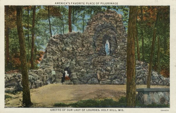 Colorized postcard of the Our Lady of Lourdes and St. Bernadette sculptures enclosed in a stone structure. Caption at top reads: "America's Favorite Place of Pilgrimage."Caption at bottom reads: "Grotto of Our Lady of Lourdes, Holy Hill, Wis." Caption on back: "Shrine of Our Lady 'Mary — Help of Christians.'"
