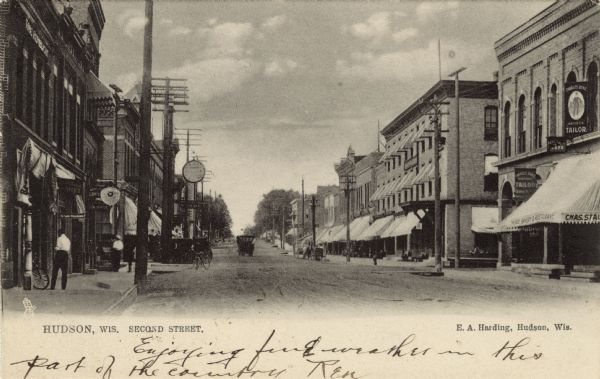 View of Second Street, a central business district. The businesses include a restaurant, a tailor, and a law office. Caption reads: "Hudson, Wis. Second Street."