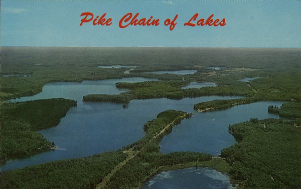 Aerial view of the Pike Chain of Lakes near Iron River, Wisconsin. Caption reads: "Pike Chain of Lakes." Text on back reads: "The ideal vacationland for fishing, swimming, boating or just loafing. Lakes are stocked with muskies, bass, northern pike, walleyes and pan-fish."