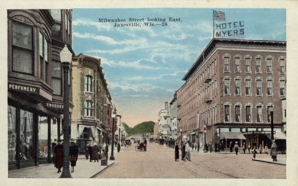Color illustration of a central street scene. The Hotel Myers is on the right, and automobiles and pedestrians are in the street. Caption reads: "Milwaukee Street looking East, Janesville, Wis."