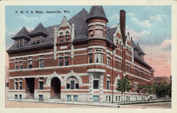 Three-quarter view across street toward the building; established 1884. There is a corner turret and an arched entrance. Caption reads: "Y.M.C.A. Building, Janesville, Wis."