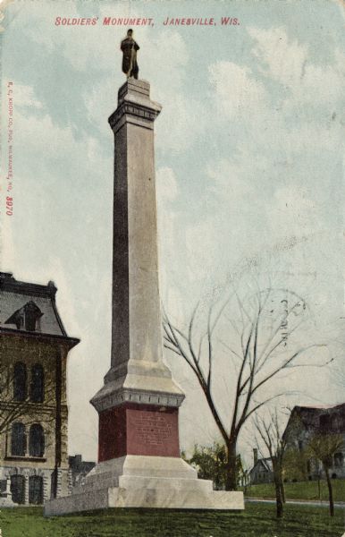 View looking up at the Soldiers' Monument, a single column with a statue of a soldier on the top. Caption reads: "Soldiers' Monument, Janesville, Wis."
