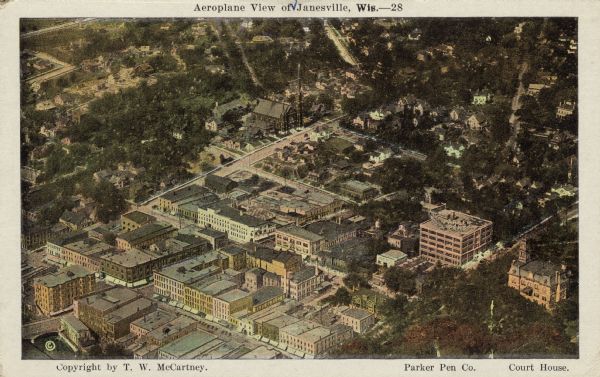 Colorized aerial view of central Janesville, with the Parker Pen building and Court House in the foreground. Caption reads: "Aeroplane View of Janesville, Wis."