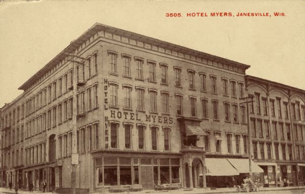 View of a four-story corner hotel on a street corner. The arched entrance has columns. An automobile is parked at the curb. Caption reads: "Hotel Myers, Janesville, Wis."