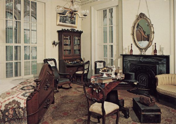Interior view of the guest bedroom furnished as it would have been in the 19th Century. There is a desk in the corner, a mirror over the fireplace, and a quilt on the bed.

Noted on reverse: "In October 1859, Abraham Lincoln was a weekend guest here. The Tallman House is the only residence in Wisconsin where Lincoln stayed."