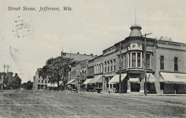 View of an intersection in downtown Jefferson. The building on the right has turret at the corner. Caption reads: "Street Scene, Jefferson, Wis."