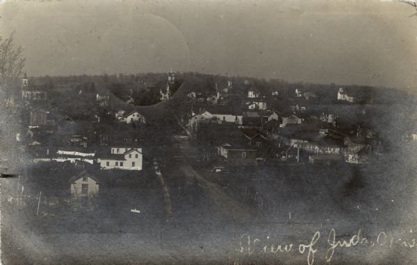 Elevated view of buildings, dwellings and churches. Caption reads: "View of Juda, Wis."