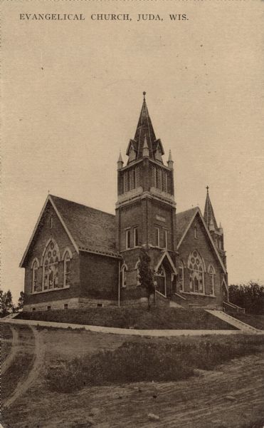 View of a large corner church with two steeples. Caption reads: "Evangelical Church, Juda, Wis."