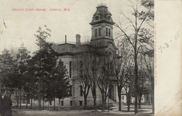 Exterior view of the county courthouse, with a tower above the entrance. A man is standing in the left foreground. Caption reads: "County Court House, Juneau, Wis."
