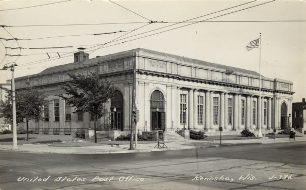 Black and white photographic postcard of a Neo-classical style building. There are street signs and a traffic light on the corner. Caption reads: "United States Post Office, Kenosha, Wis."