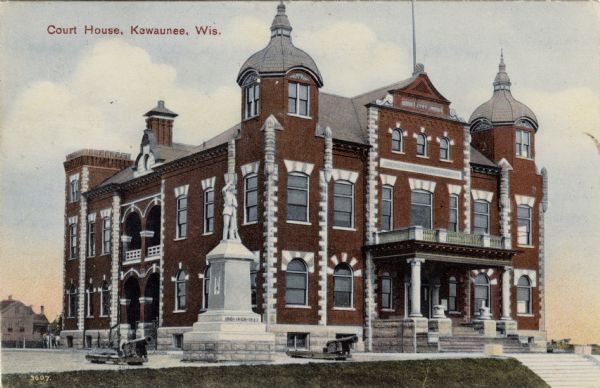 Colorized postcard view of the Kauwaunee County Courthouse and adjoining veterans' memorial. The monument is flanked by cannons. Caption reads: "Court House, Kewaunee, Wis."