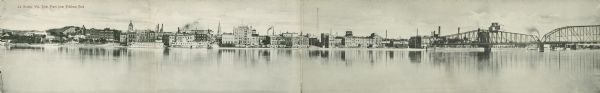 View across Mississippi River towards the La Crosse waterfront. Postcard is folded in four parts, and text on front reads: "Mail Card. Write on back of this card only your name and address. Put rubber-band around folder card."
