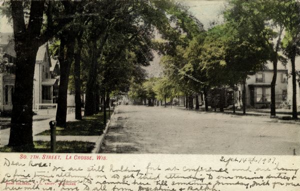 View down a tree-lined residential street. Hitching posts are along the curbs. Caption reads: "So. 7th Street, La Crosse, Wis."