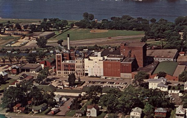Aerial view of brewery, with the Mississippi River in the background. Text on reverse reads: "Aerial view of G. Heilman Brewing Co., Inc., La Crosse, Wisc., brewers of world famous Old Style and Special Export beers. Within these walls, the Mariners Return Beer Stube, replica of Fritz Wagner's great painting, is a popular tourist attraction, enjoyed by thousands of visitors each year."