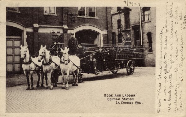 A group of fire fighters are posing on a horse-drawn hook and ladder firetruck parked at the entrance of the firehouse. Caption reads: "Hook and Ladder Central Station, La Crosse, Wis."