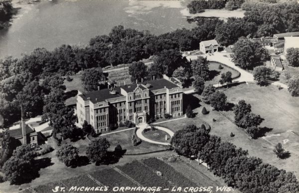Aerial view of an orphanage and grounds near the Mississippi River. Caption reads: "St. Michael's Orphanage — La Crosse, Wis."