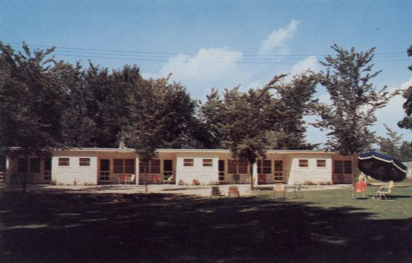 View of a row of units at the Bluff View Motel. Patio furniture and umbrellas are on the lawn.

Text on reverse reads: "Bluff View Motel, Route 1, La Crosse, Wis., U.S. Highway 14-61-35. Completely modern rooms. Restful surroundings. A.A.A. approved. Owners-Mgrs, Mr. & Mrs. M.W. Miller."