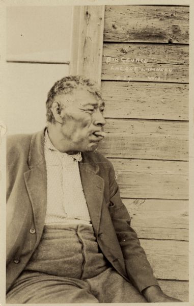 Portrait of an old Ojibwa man smoking a cigar.