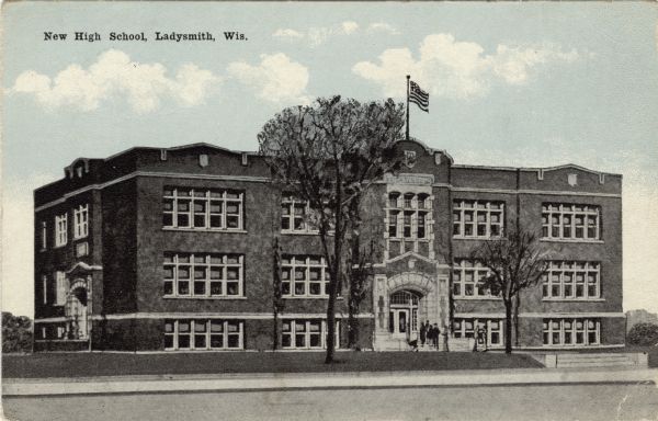 View across street towards the high school, with people gathered on the front steps. Caption reads: "New High School, Ladysmith, Wis."