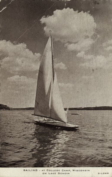 Photographic postcard view of a sailboat on Lake Geneva. A woman is standing on the deck. Caption reads: "Sailing &#8212; at College Camp, Wisconsin On Lake Geneva."