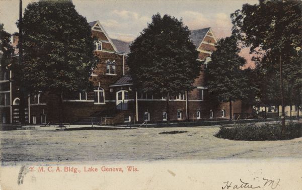 View across driveway towards the YMCA building, with red brick with a gabled roof. Caption reads: "Y.M.C.A. Bldg., Lake Geneva, Wis."