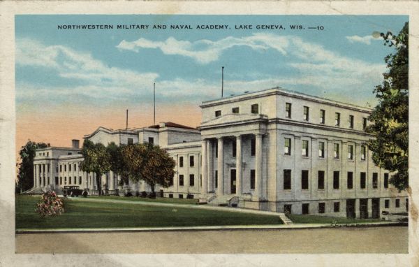 View across street towards a broad lawn, and a Neo-Classical building with columns at the entrances. An automobile is parked at the central entrance on the left. Caption reads: "Northwestern Military and Naval Academy, Lake Geneva, Wis."