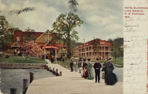 Hand-colored postcard view down pier towards a lakeside hotel. Tourists are standing on the pier, and are also on the lawn. A sign at the shoreline framing the pier reads: "Glenwood Springs." Caption reads: "Hotel Glenwood, Lake Geneva, P.O. Fontana, Wis."