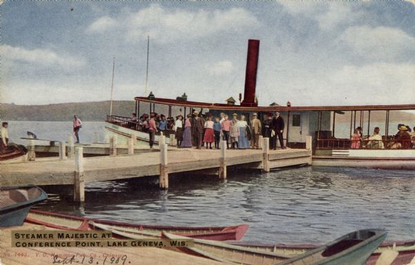 Hand-colored postcard view from shoreline towards tourists embarking on an excursion boat; some of the people are on the boat, and others are standing on the pier. Boats are moored to a landing in the foreground. Caption reads: "Steamer Majestic at Conference Point, Lake Geneva, Wis."