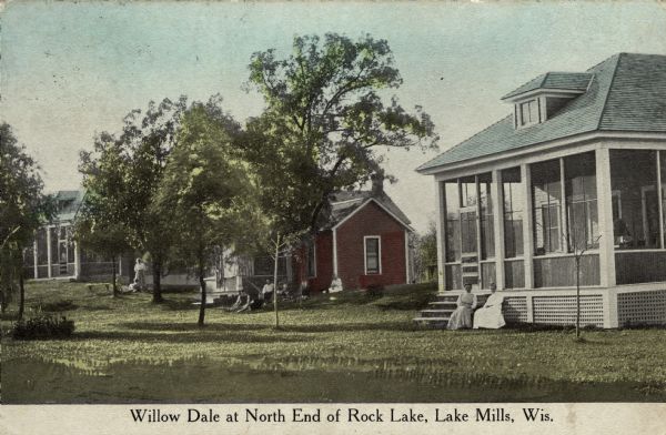 A row of three small cabins with screened-in porches. Groups of people are sitting in front of each cabin. Caption reads: "Willow Dale at North End of Rock Lake, Lake Mills, Wis."