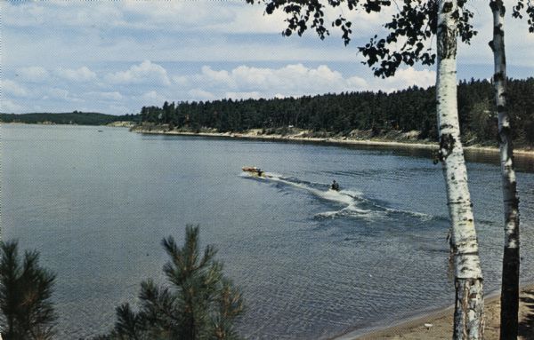 Elevated view from hill of a waterskier and motorboat on Rock Lake.