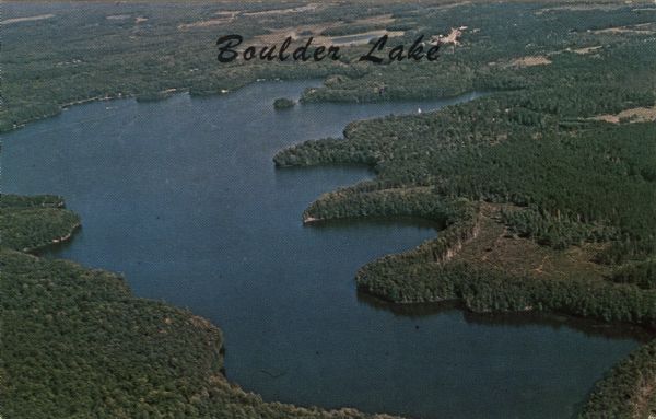 Full color aerial view of a lake surrounded by forests. Caption reads: "Boulder Lake."
