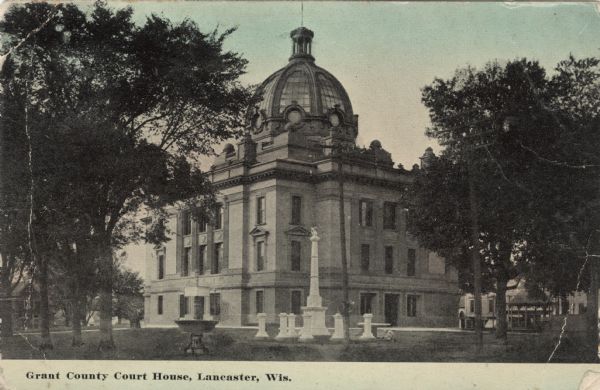 Corner view of the Grant County courthouse. The Soldiers' Monument and a fountain are in the foreground. A gazebo is under the trees on the right. Caption reads: "Grant County Court House, Lancaster, Wis."